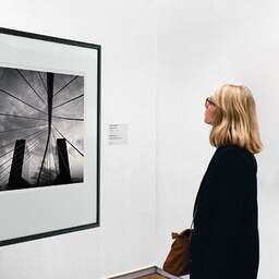 Art and collection photography Denis Olivier, Bridge And Buildings, Bilbao, Spain. February 2022. Ref-11532 - Denis Olivier Art Photography, A woman contemplate a large original photographic art print in limited edition and signed in a black frame