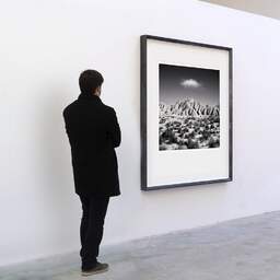 Art and collection photography Denis Olivier, Cloud Over Dry Hills, Bardenas Reales, Spain. February 2022. Ref-11577 - Denis Olivier Art Photography, A visitor contemplate a large original photographic art print in limited edition and signed in a black frame