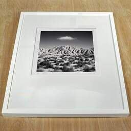Art and collection photography Denis Olivier, Cloud Over Dry Hills, Bardenas Reales, Spain. February 2022. Ref-11577 - Denis Olivier Art Photography, white frame on a wooden table