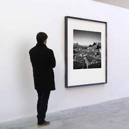 Art and collection photography Denis Olivier, French Village, Saint-Emilion, France. October 2022. Ref-11590 - Denis Olivier Art Photography, A visitor contemplate a large original photographic art print in limited edition and signed in a black frame