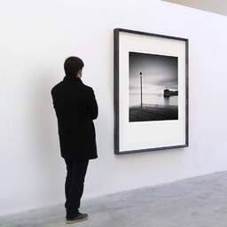 Art and collection photography Denis Olivier, Harbour Entrance, Bourcefranc-Le-Chapus, France. November 2021. Ref-11554 - Denis Olivier Art Photography, A visitor contemplate a large original photographic art print in limited edition and signed in a black frame