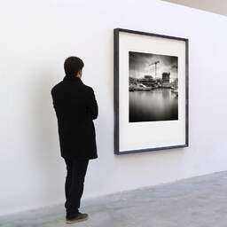 Art and collection photography Denis Olivier, Marina, Dock 2, Bordeaux, France. August 2020. Ref-1359 - Denis Olivier Art Photography, A visitor contemplate a large original photographic art print in limited edition and signed in a black frame