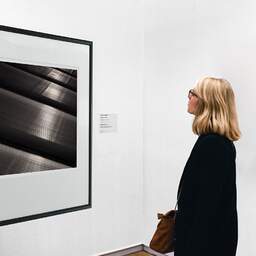 Art and collection photography Denis Olivier, Metallic, Poitiers, France. June 1990. Ref-919 - Denis Olivier Art Photography, A woman contemplate a large original photographic art print in limited edition and signed in a black frame