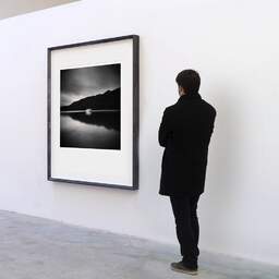 Art and collection photography Denis Olivier, Moving Boat, Lake Okataina, New Zealand. July 2018. Ref-1318 - Denis Olivier Art Photography, A visitor contemplate a large original photographic art print in limited edition and signed in a black frame