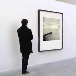 Art and collection photography Denis Olivier, Pier End, Keiss Harbour Broch, Scotland. April 2006. Ref-984 - Denis Olivier Art Photography, A visitor contemplate a large original photographic art print in limited edition and signed in a black frame