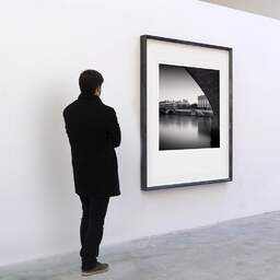 Art and collection photography Denis Olivier, Quai De La Corse, Paris, France. February 2022. Ref-11599 - Denis Olivier Art Photography, A visitor contemplate a large original photographic art print in limited edition and signed in a black frame