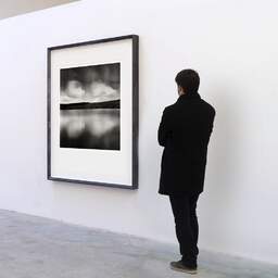 Art and collection photography Denis Olivier, Reflecting Clouds, Sauvages Lake, France. August 2020. Ref-1422 - Denis Olivier Art Photography, A visitor contemplate a large original photographic art print in limited edition and signed in a black frame