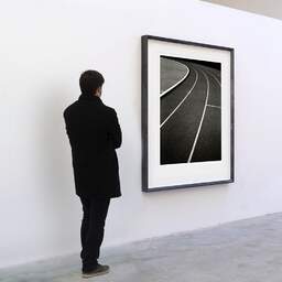 Art and collection photography Denis Olivier, Running Track, Etude 2, Leo Lagrange Stadium, Saint-Nazaire, France. November 2022. Ref-11644 - Denis Olivier Art Photography, A visitor contemplate a large original photographic art print in limited edition and signed in a black frame