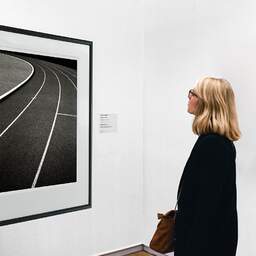 Art and collection photography Denis Olivier, Running Track, Etude 2, Leo Lagrange Stadium, Saint-Nazaire, France. November 2022. Ref-11644 - Denis Olivier Art Photography, A woman contemplate a large original photographic art print in limited edition and signed in a black frame