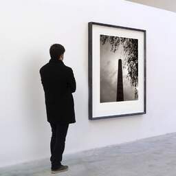 Art and collection photography Denis Olivier, Smokestack, Vertou, France. August 2021. Ref-11604 - Denis Olivier Art Photography, A visitor contemplate a large original photographic art print in limited edition and signed in a black frame