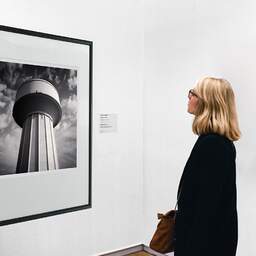 Art and collection photography Denis Olivier, Water Tower, Haut-Brion, Pessac, France. October 2022. Ref-11598 - Denis Olivier Art Photography, A woman contemplate a large original photographic art print in limited edition and signed in a black frame